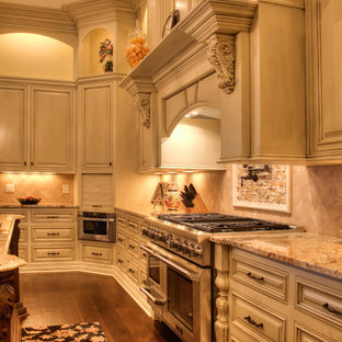 Offene, Geräumige Klassische Küche in U-Form mit Kücheninsel, Schränken im Used-Look, Granit-Arbeitsplatte, Küchenrückwand in Beige, Rückwand aus Steinfliesen, Küchengeräten aus Edelstahl, Landhausspüle, dunklem Holzboden und profilierten Schrankfronten in Sonstige