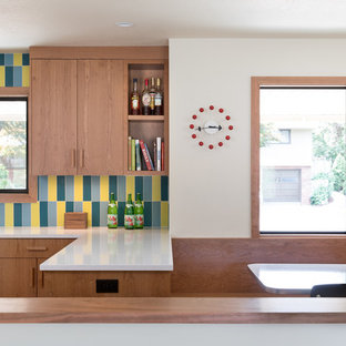 Large midcentury u-shaped eat-in kitchen in Portland with an undermount sink, flat-panel cabinets, medium wood cabinets, multi-coloured splashback, ceramic splashback, stainless steel appliances, light hardwood floors, a peninsula, white benchtop and recycled glass benchtops.
