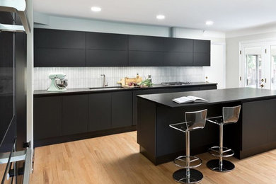 Inspiration for a mid-sized transitional light wood floor eat-in kitchen remodel in Detroit with an undermount sink, glass-front cabinets, black cabinets, granite countertops, white backsplash, ceramic backsplash, paneled appliances and an island