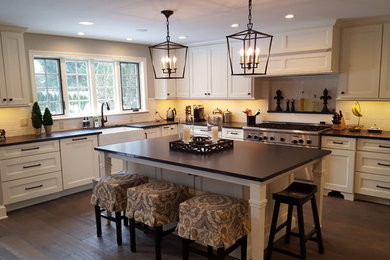 Large transitional l-shaped dark wood floor and brown floor open concept kitchen photo in Detroit with a farmhouse sink, recessed-panel cabinets, white cabinets, granite countertops, white backsplash, subway tile backsplash, an island and stainless steel appliances