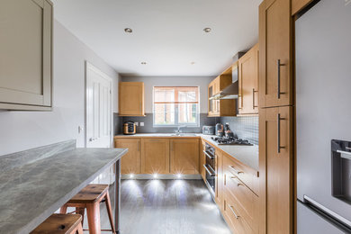 Cette image montre une petite cuisine design en L et bois brun fermée avec un placard à porte shaker, une crédence grise, une crédence en céramique, un sol en vinyl et un sol gris.