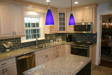 Example of a mid-sized trendy l-shaped vinyl floor enclosed kitchen design in Richmond with an undermount sink, raised-panel cabinets, light wood cabinets, granite countertops, gray backsplash, glass tile backsplash, stainless steel appliances and an island