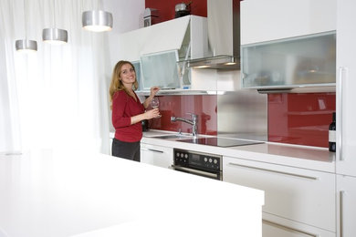 Foto de cocina comedor moderna con salpicadero rojo, salpicadero de vidrio templado y armarios tipo vitrina