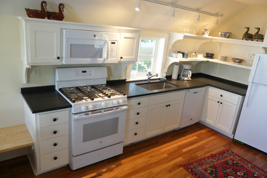 Example of a small classic l-shaped eat-in kitchen design in Burlington with flat-panel cabinets, white cabinets and no island