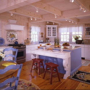 Photo of a l-shaped kitchen in Boston with a drop-in sink, white cabinets, stainless steel appliances, medium hardwood floors and with island.