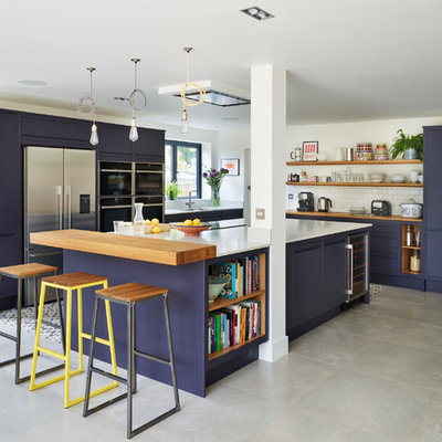 Example of a beach style l-shaped gray floor kitchen design in Surrey with an undermount sink, flat-panel cabinets, blue cabinets, wood countertops, white backsplash, subway tile backsplash, stainless steel appliances and an island