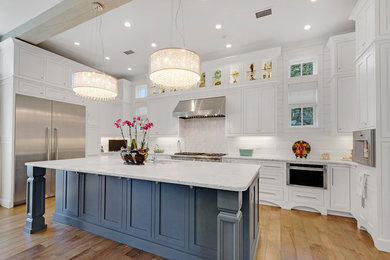 Inspiration for a large transitional u-shaped light wood floor and brown floor kitchen remodel in Miami with an undermount sink, shaker cabinets, white backsplash, stainless steel appliances, an island, white cabinets, quartzite countertops and wood backsplash