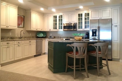 Klassische Wohnküche mit Küchengeräten aus Edelstahl, Kücheninsel, weißen Schränken, Granit-Arbeitsplatte und Porzellan-Bodenfliesen in Tampa