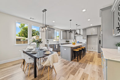 Open concept kitchen - mid-sized transitional u-shaped laminate floor open concept kitchen idea in Sacramento with a farmhouse sink, shaker cabinets, gray cabinets, quartzite countertops, white backsplash, subway tile backsplash, stainless steel appliances, an island and gray countertops