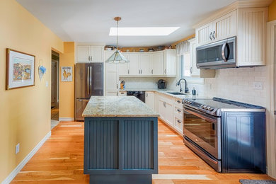 Photo of a medium sized rural l-shaped enclosed kitchen in Toronto with a submerged sink, shaker cabinets, white cabinets, granite worktops, white splashback, metro tiled splashback, stainless steel appliances, medium hardwood flooring, an island, brown floors and beige worktops.