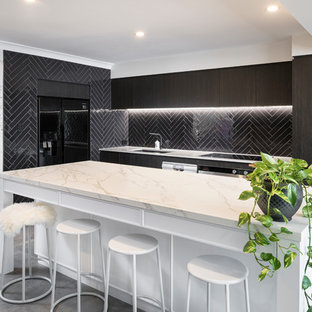 Photo of a mid-sized contemporary galley kitchen in Perth with an undermount sink, flat-panel cabinets, dark wood cabinets, black splashback, subway tile splashback, black appliances, cement tiles, with island, grey floor, white benchtop and marble benchtops.