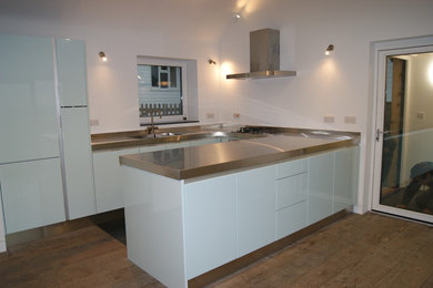 Inspiration for a medium sized modern u-shaped kitchen/diner in Cambridgeshire with a submerged sink, blue cabinets, stainless steel worktops, slate flooring and flat-panel cabinets.