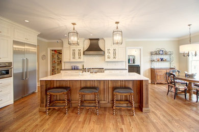 Large cottage l-shaped medium tone wood floor eat-in kitchen photo in Denver with a farmhouse sink, raised-panel cabinets, dark wood cabinets, marble countertops, white backsplash, ceramic backsplash, stainless steel appliances, an island and white countertops