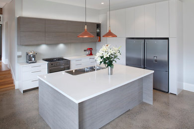 Moderne Wohnküche in L-Form mit Doppelwaschbecken, hellen Holzschränken, Küchengeräten aus Edelstahl, Kücheninsel, Quarzwerkstein-Arbeitsplatte, Glasrückwand und weißer Arbeitsplatte in Sydney