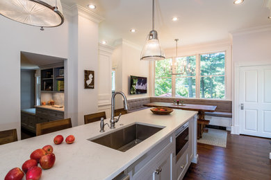 Large transitional l-shaped dark wood floor and brown floor eat-in kitchen photo in Philadelphia with a farmhouse sink, shaker cabinets, white cabinets, gray backsplash, stainless steel appliances, an island, white countertops, marble countertops and marble backsplash