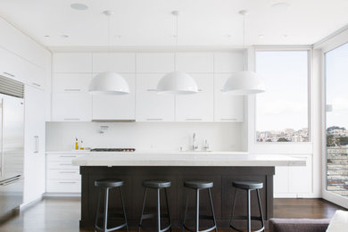 Inspiration for a contemporary l-shaped open plan kitchen in San Francisco with a submerged sink, flat-panel cabinets, white cabinets, stainless steel appliances, dark hardwood flooring, an island, brown floors and white worktops.