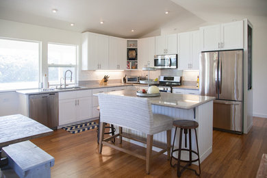Open concept kitchen - mid-sized country l-shaped medium tone wood floor open concept kitchen idea in Hawaii with an undermount sink, shaker cabinets, white cabinets, granite countertops, white backsplash, subway tile backsplash, stainless steel appliances and an island
