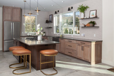 Mid-sized trendy u-shaped gray floor and porcelain tile kitchen photo in Other with an island, medium tone wood cabinets, stainless steel appliances, gray countertops, a farmhouse sink, shaker cabinets, quartz countertops, white backsplash and brick backsplash