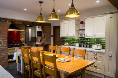 Imagen de cocina comedor tradicional de tamaño medio con armarios estilo shaker, encimera de acrílico, salpicadero rojo, salpicadero de vidrio templado, suelo vinílico, suelo gris y una isla