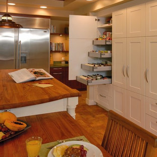 Inspiration for a tropical eat-in kitchen in Hawaii with stainless steel appliances, wood benchtops, shaker cabinets, white cabinets and cork floors.