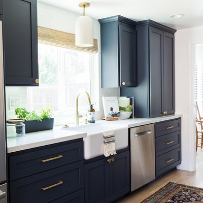 Kitchen - country medium tone wood floor and beige floor kitchen idea in Sacramento with a farmhouse sink, shaker cabinets, black cabinets, white backsplash, brick backsplash, stainless steel appliances, no island and white countertops