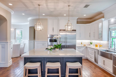 Inspiration for a large classic l-shaped kitchen/diner in Orange County with a built-in sink, quartz worktops, white splashback, stone slab splashback, stainless steel appliances, an island, beaded cabinets, white cabinets and medium hardwood flooring.
