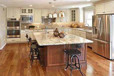 Large transitional l-shaped medium tone wood floor eat-in kitchen photo in DC Metro with an undermount sink, raised-panel cabinets, white cabinets, granite countertops, gray backsplash, ceramic backsplash, stainless steel appliances and an island