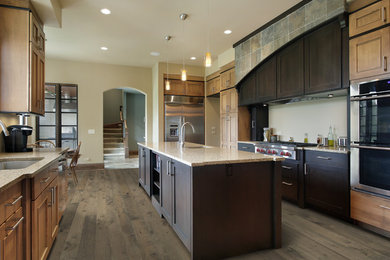 Cette image montre une grande cuisine américaine design avec un électroménager en acier inoxydable, un sol en bois brun et îlot.