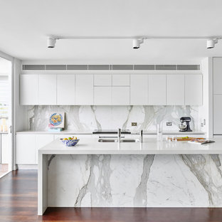 Inspiration for a contemporary galley kitchen in Brisbane with an undermount sink, flat-panel cabinets, white cabinets, grey splashback, stone slab splashback, stainless steel appliances, dark hardwood floors, with island and brown floor.