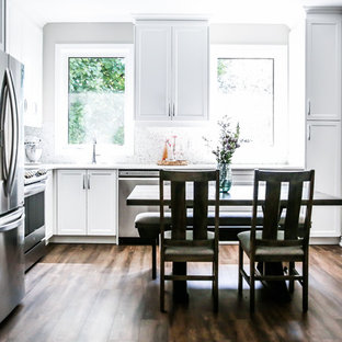 This is an example of a mid-sized tropical single-wall open plan kitchen in Toronto with a double-bowl sink, white cabinets, quartzite benchtops, white splashback, porcelain splashback, stainless steel appliances, vinyl floors, no island and white benchtop.