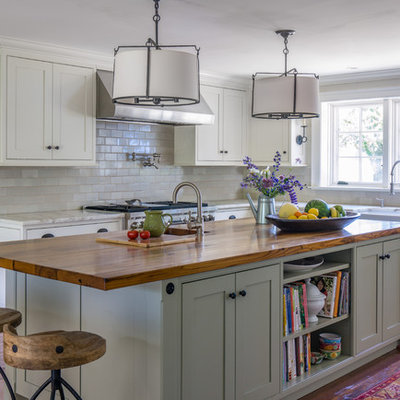Eat-in kitchen - large farmhouse l-shaped medium tone wood floor eat-in kitchen idea in Boston with a farmhouse sink, recessed-panel cabinets, white cabinets, wood countertops, white backsplash, ceramic backsplash, stainless steel appliances and an island