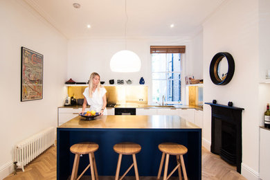 ロンドンにあるコンテンポラリースタイルのおしゃれなキッチン (フラットパネル扉のキャビネット、白いキャビネット、白い調理設備、無垢フローリング) の写真