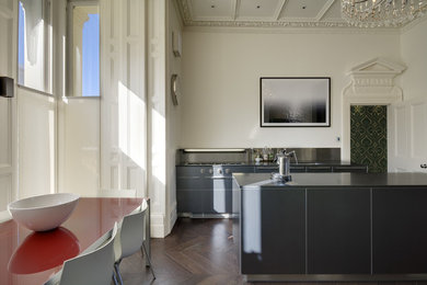 Bild på ett stort funkis grå grått kök, med en nedsänkt diskho, släta luckor, grå skåp, bänkskiva i koppar, stänkskydd med metallisk yta, rostfria vitvaror, mörkt trägolv, en köksö och brunt golv