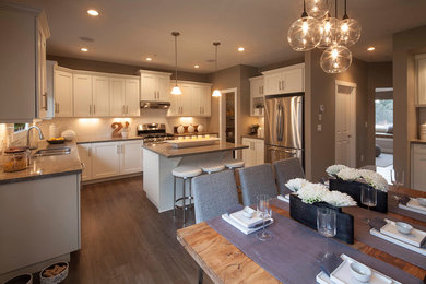 Eat-in kitchen - transitional dark wood floor eat-in kitchen idea in Vancouver with a double-bowl sink, shaker cabinets, white cabinets, white backsplash, subway tile backsplash, stainless steel appliances and an island