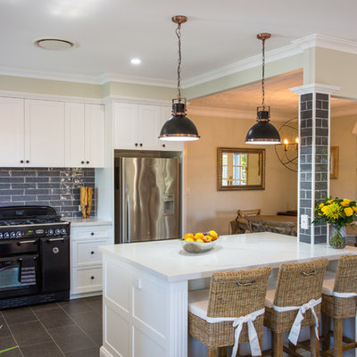 Example of a large classic l-shaped ceramic tile and gray floor open concept kitchen design in Brisbane with an undermount sink, shaker cabinets, white cabinets, quartz countertops, gray backsplash, black appliances and an island