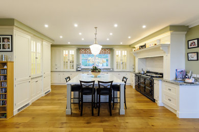 Exempel på ett klassiskt kök, med en rustik diskho, luckor med infälld panel, vita skåp, granitbänkskiva, vitt stänkskydd och en köksö
