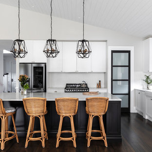 Inspiration for a transitional l-shaped kitchen in Brisbane with a farmhouse sink, shaker cabinets, white cabinets, white splashback, stainless steel appliances, dark hardwood floors, with island, brown floor and white benchtop.