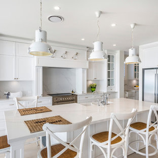 Inspiration for a large beach style galley eat-in kitchen in Gold Coast - Tweed with a farmhouse sink, shaker cabinets, white cabinets, marble benchtops, white splashback, marble splashback, stainless steel appliances, ceramic floors, with island, beige floor and white benchtop.