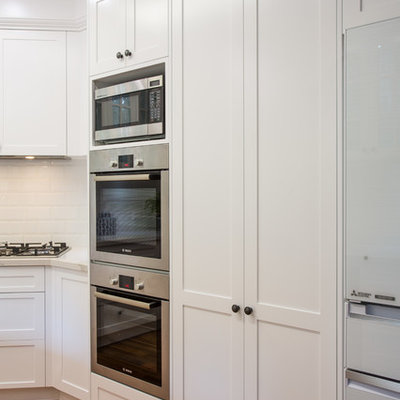 Inspiration for a large timeless u-shaped medium tone wood floor and brown floor open concept kitchen remodel in Brisbane with a double-bowl sink, shaker cabinets, white cabinets, quartz countertops, white backsplash, subway tile backsplash, black appliances and an island