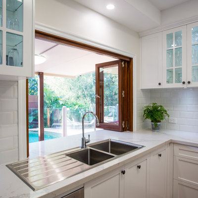 Inspiration for a large timeless u-shaped medium tone wood floor and brown floor open concept kitchen remodel in Brisbane with a double-bowl sink, shaker cabinets, white cabinets, quartz countertops, white backsplash, subway tile backsplash, black appliances and an island