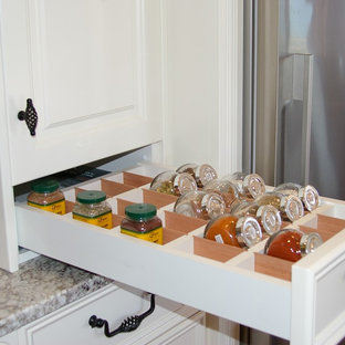 This is an example of a mid-sized shabby-chic style galley open plan kitchen in Adelaide with a farmhouse sink, raised-panel cabinets, beige cabinets, granite benchtops, multi-coloured splashback, glass sheet splashback, black appliances, medium hardwood floors, with island and brown floor.