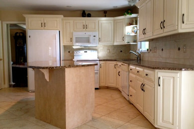 Elegant kitchen photo in Other with raised-panel cabinets, granite countertops and stone tile backsplash