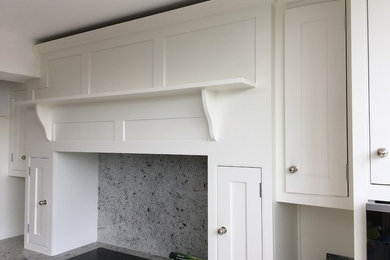 Photo of a medium sized contemporary galley open plan kitchen in Surrey with shaker cabinets, white cabinets, granite worktops, multi-coloured splashback, white appliances, ceramic flooring, an island and multicoloured worktops.