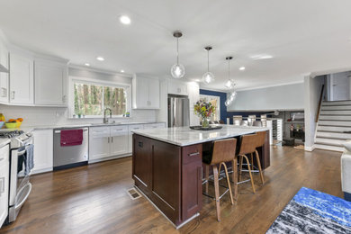 Large elegant galley medium tone wood floor and brown floor eat-in kitchen photo in Atlanta with a single-bowl sink, raised-panel cabinets, white cabinets, quartz countertops, white backsplash, ceramic backsplash, stainless steel appliances, an island and white countertops