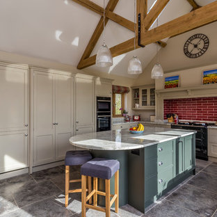 Large rural l-shaped kitchen in Hertfordshire with recessed-panel cabinets, red splashback, metro tiled splashback, an island, grey floors and grey worktops.