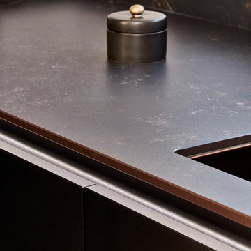 Handle-less Black kitchen with Copper accents & bespoke Concrete breakfast bar