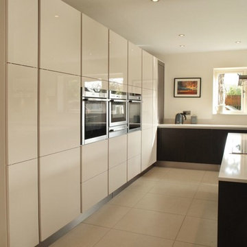 Handle-less high gloss cashmere & black kitchen with tall storage units