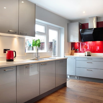 Handled, high gloss grey kitchen with red splashback