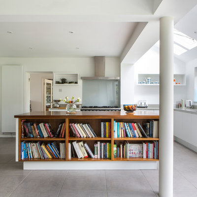 Eat-in kitchen - mid-sized modern l-shaped gray floor eat-in kitchen idea in Oxfordshire with flat-panel cabinets, white cabinets, solid surface countertops, an island, an undermount sink, glass sheet backsplash and stainless steel appliances