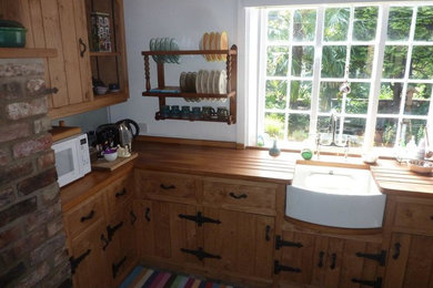 Modelo de cocina comedor lineal clásica pequeña sin isla con fregadero sobremueble, puertas de armario de madera oscura y encimera de madera